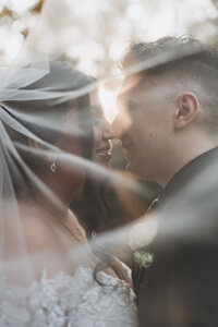 bride and groom kissing under veil