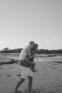 guy giving his girlfriend a piggy back ride on cape cod beach