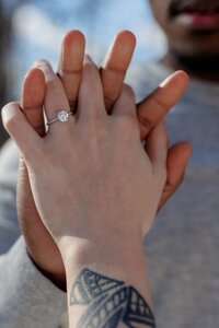 A glossy photograph taken by Studio Roscher of a happy engaged couple with a ring outside in a park in Richmond, VA