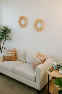 beige couch in a therapy room with pillows and end table