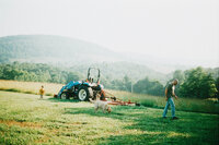 A film photo of a father son and dog in front of a tractor in the mountains