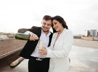 Bride and groom pouring champagne together during rooftop wedding portraits in downtown San Antonio.