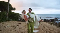 Groom on the beach with bride in a green suit at sunset