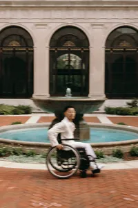 Intentionally blurry image of human looking at camera with fountain and large building in the background