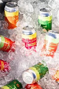 Close up of seven cans of a variety of flavors of Anytime drink in ice