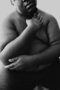 Close up black and white image of human lightly hugging their arms around their body