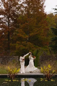 Outdoor photo with big trees and couple holding flowers and holding hands and spinning