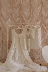 White silk garments hung up in front of a peach silk background