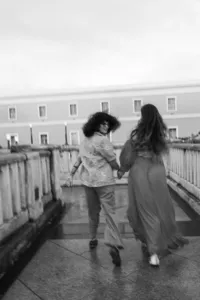 Black and white image of humans walking away from the camera, one looking back at the other.
