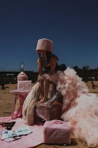 Human sitting with fluffy, pink tulle dress outside with pink hat on
