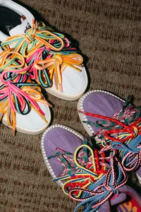 Two pairs of shoes with fun, colorful laces with their tops pressed against each other