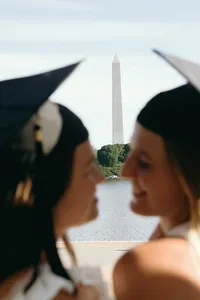 Two humans smiling while faces are close to one another with statement building in the background
