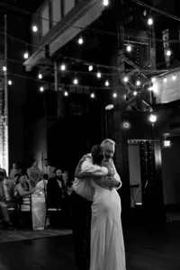 Black and white image of two humans hugging one another at celebration of love reception