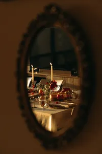 Looking inside an oval window that has place settings with gold tablecloth, decor and tall candles lit