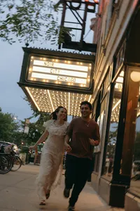 Couple holding hands and walking outside theatre that has a sign that says Noir City Chicago