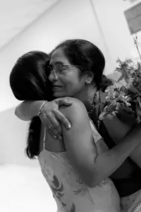 Black and white image of two humans hugging while one is holding flowers