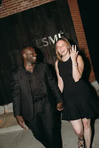 Couple standing next to one another and one is holding up their hand to show off ring