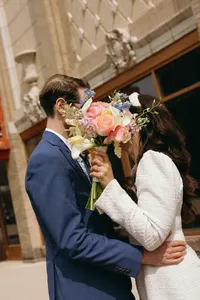 Couple kissing with a colorful bouquet of flowers covering their faces