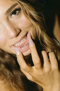 Individual pulling bottom lip out to show lip tattoo