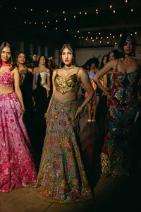 Multiple fashion forward humans all looking at the camera with beautiful, colorful dresses