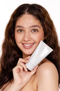 Human holding white bottle in front of their face with white background