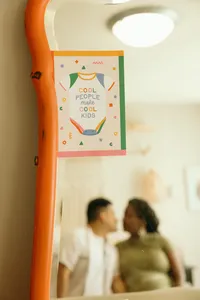 Couple underneath sign that says 'Cool people make cool kids'
