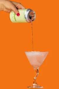 Anytime drink being poured into a cocktail glass with an orange background