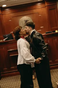 Couple holding hands and kissing one another at celebration of love ceremony in courthouse