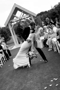 Black and white image of couple walking down the aisle and kissing and being dipped