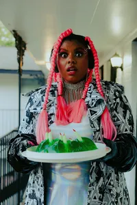 Human with hot pink hair with four braids and a black and white outfit holding plate