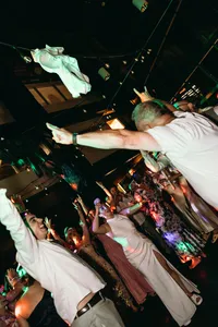Couple with hands up in the air celebrating at celebration of love reception with colorful lights
