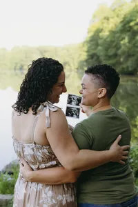Two humans looking at one another and smiling while holding sonogram image