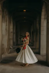 Human in white silk dress while holding colorful bouquet of flowers
