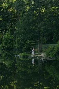 Human standing in the distance in a blue dress with greenery surrounding them