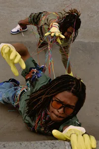 Human laying down and wearing sunglasses, green shirt and yellow gloves