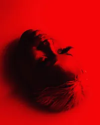 Black and red close up image of face with human looking upwards and away from the camera