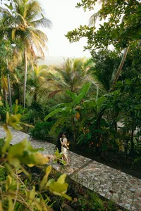 Two humans embracing on the sidewalk with greenery surrounding them