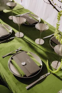 Formal place settings with pea green tablecloth and napkins and menus on top of the napkins
