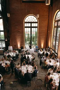 Overhead shot of celebration of love reception with circular white tables and venue with floor to ceiling windows