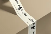 Crème de la Crème branded packing tape wrapped around a neutral shipping box.