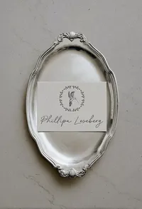 Phillipa Leseberg logo and illustrated hummingbird brandmark displayed on a card in a vintage silver tray.