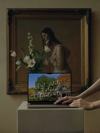 Tami Luger Real Estate services page on a laptop beneath a framed portrait painting