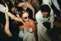 Rachael in sunglasses dancing with friends on a packed dance floor at her Charleston wedding reception