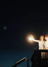 A couple holding up a lantern on a fire lookout