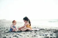 Minneapolis family photographer capturing young children playing together during a beach family session in Minnesota.