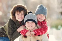 Three siblings smiling together outdoors in winter by Elissa Bean Photography, family photographer serving Edina and Minneapolis