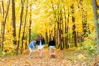 Three siblings walking their dog through colorful fall woods by Elissa Bean Photography, family photographer serving Minnetonka and Minneapolis.