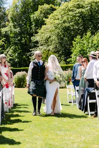 Bride and groom walking through their outdoor wedding ceremony as guests look on