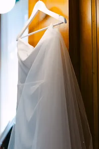 Wedding dress hanging in a sunlit room before the ceremony