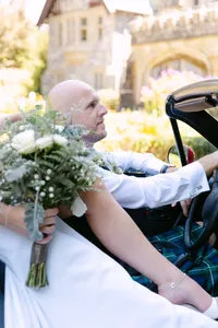 Newlyweds riding together in a red vintage car